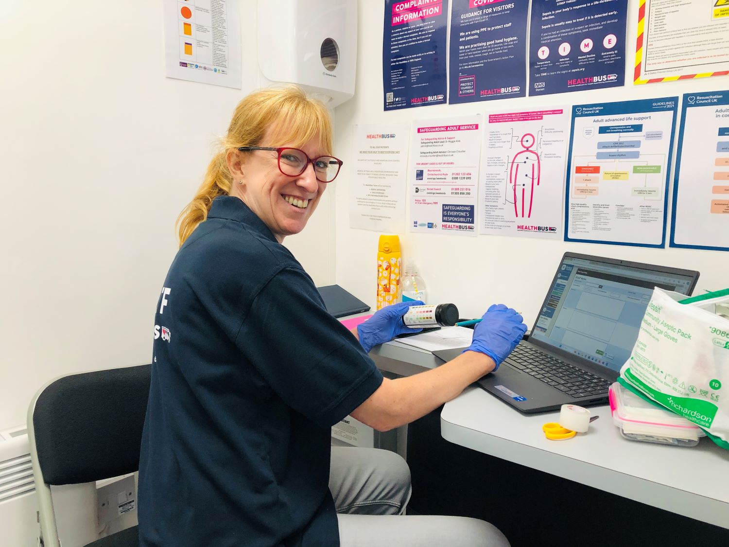 Lady at a computer with medical gloves on turning and smiling to camera
